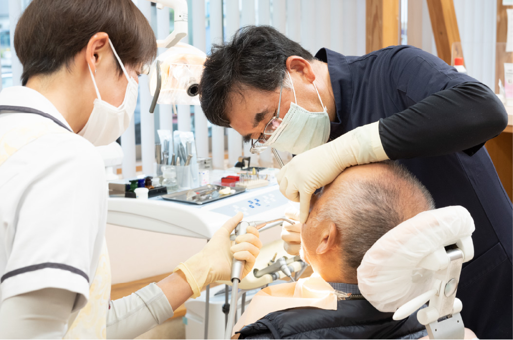 ご高齢の患者さんの治療を行う院長森山隆平と歯科衛生士